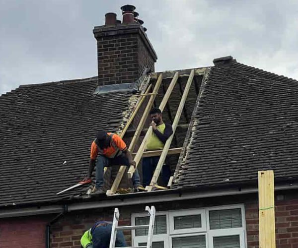 This is a photo of a roof repair being carried out. A section of the roof has been stripped and two roofers are replacing the rafters. Works being carried out by ES Roofing Adwick Le Street